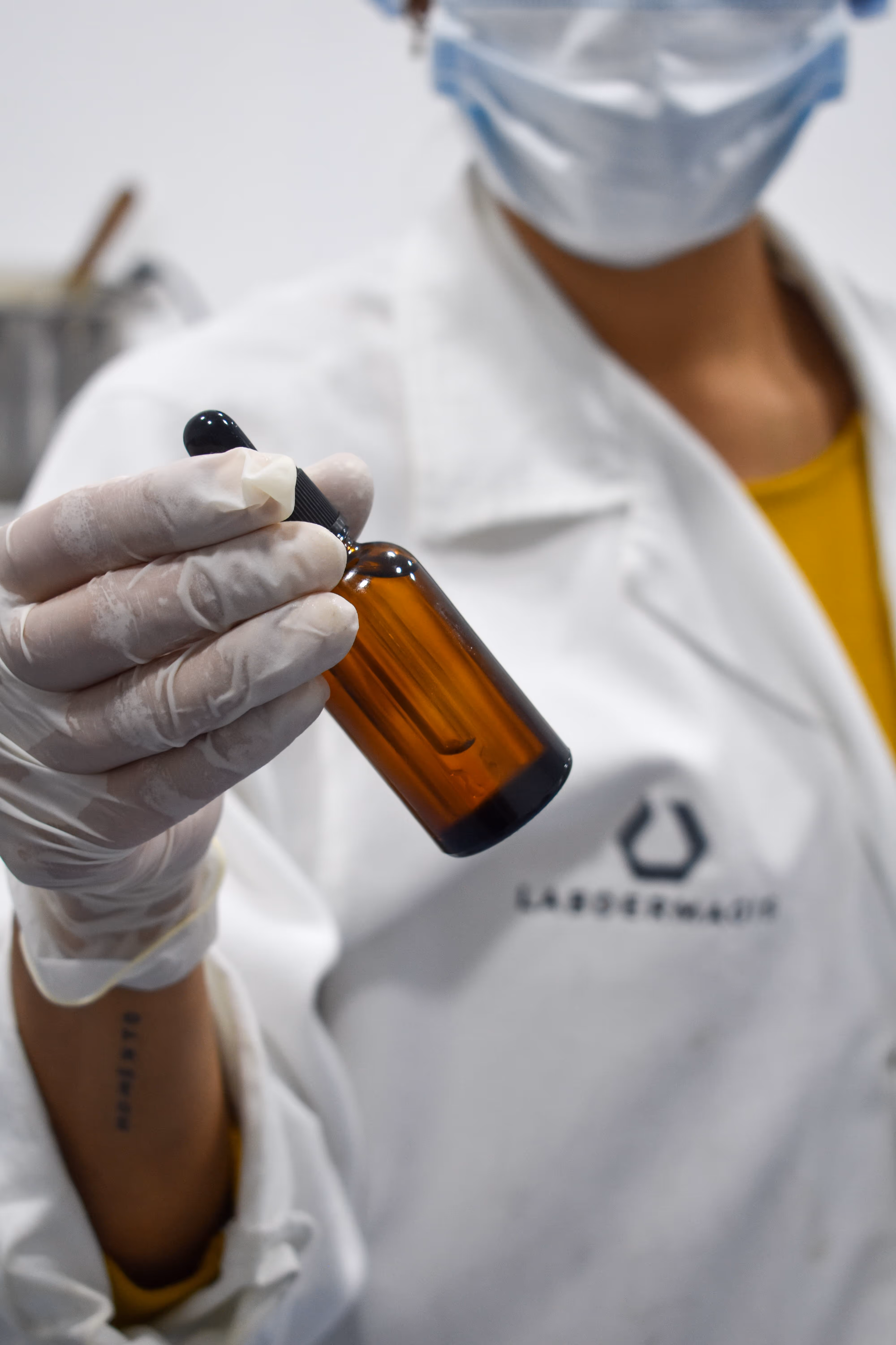Persona en laboratorio sosteniendo un frasco con gotero